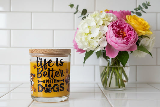 Candle jar with 'life is better with dogs' text and paw prints on a white background