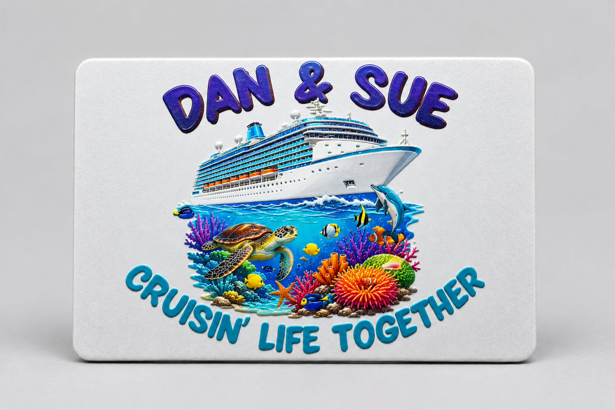 A rectangular white card or plaque featuring a colorful cruise-themed illustration with a large cruise ship, underwater coral reef, sea turtle, fish, and raised blue text reading 'Cruising Life Together' and 'Daw & Sue', placed on a teal background.