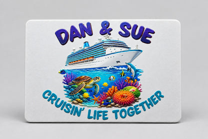 A rectangular white card or plaque featuring a colorful cruise-themed illustration with a large cruise ship, underwater coral reef, sea turtle, fish, and raised blue text reading 'Cruising Life Together' and 'Daw & Sue', placed on a teal background.