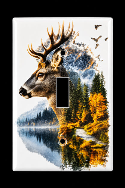 A rectangular light switch plate cover featuring a detailed nature design with a deer head, forest trees, autumn foliage, and a reflective lake, shown against a dark background.