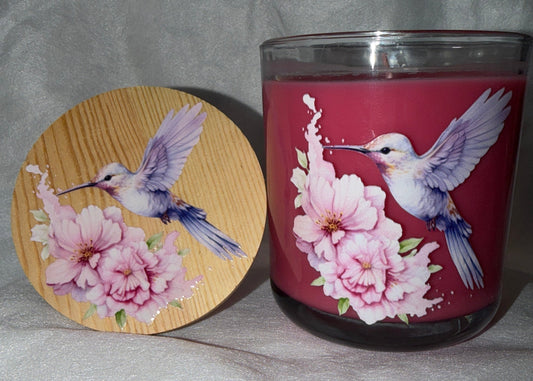 Candle with a hummingbird and floral design on a soft white surface