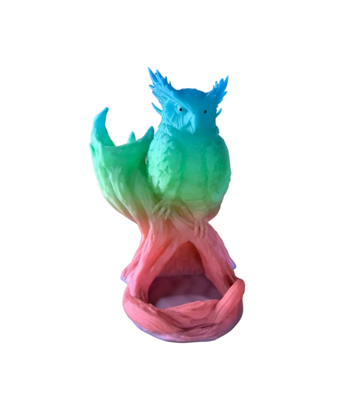 A colorful owl perched on a tree branch-shaped structure, with a blue-to-green-to-pink gradient finish, displayed on a wooden surface in a store setting.