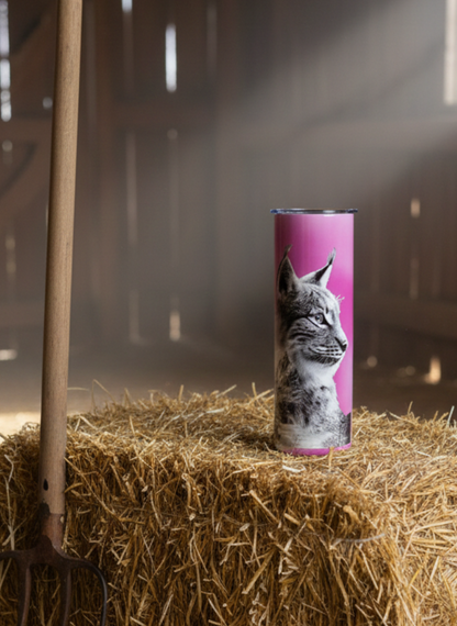 Candle with a cat design on a hay bale in a barn setting