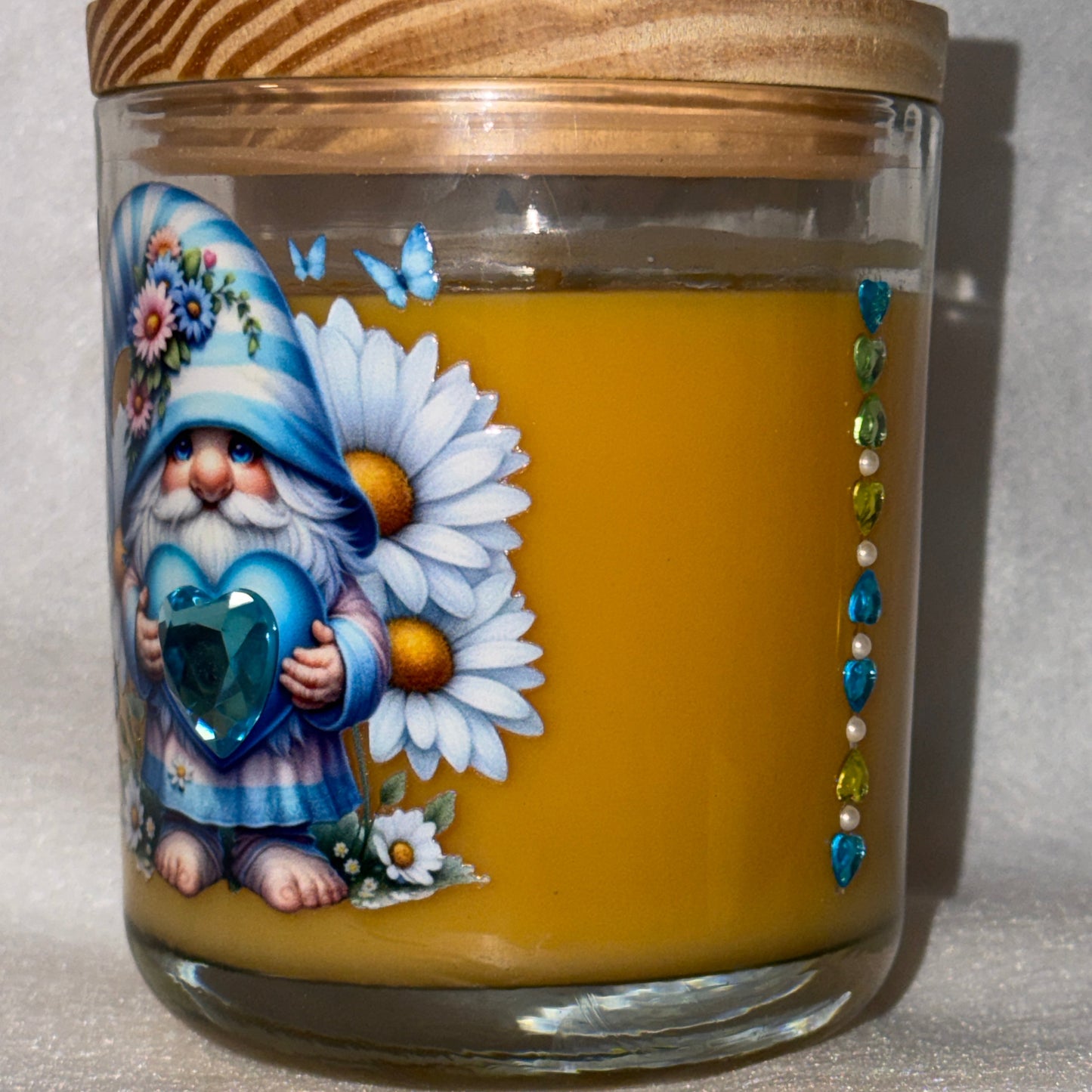 Decorative glass jar with wooden lid featuring a painted design of a gnome  holding a heart with flowers.