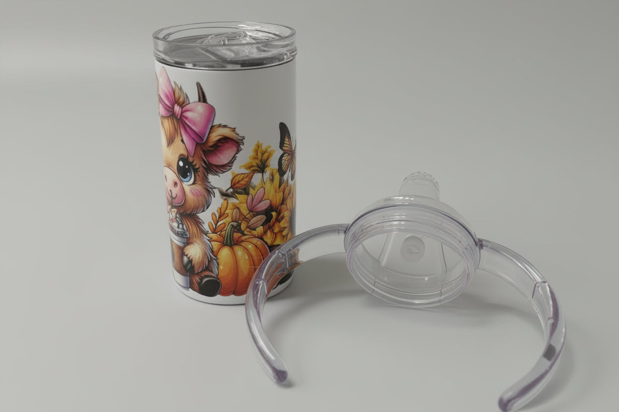 Tumbler with animal design and clear baby bottle nipple on a white surface