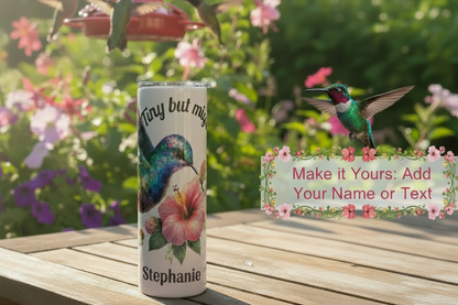 Tumbler with floral design and text on a wooden surface with flowers in the background